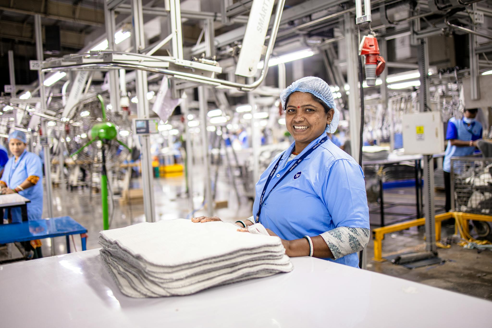 Cheerful female worker in blue uniform at a textile plant.