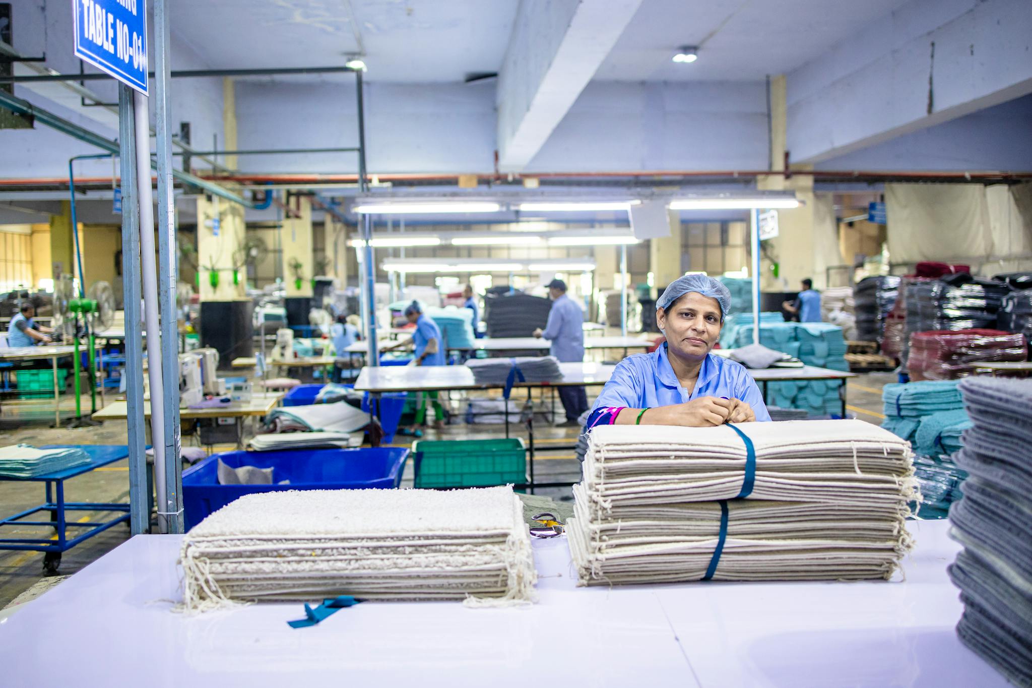 Female worker organizing textile bundles in an industrial factory setting, showcasing blue-collar labor.
