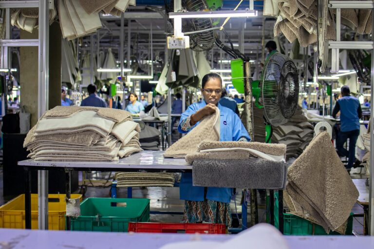 Woman organizing textile products in a bustling factory environment.
